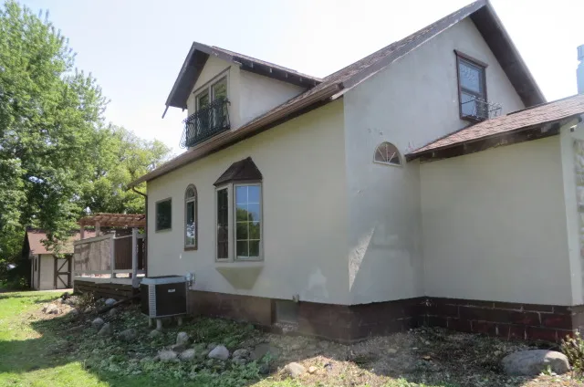 After: The same stucco house with the brush cleared and the wall and windows visible