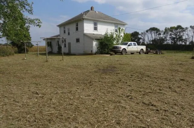 After: The same farmhouse yard mowed short, with a pickup parked by the house