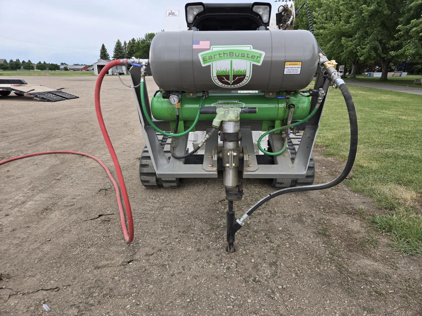 RDT’s EarthBuster deep-soil decompactor mounted on a compact track loader, with its probe and air hose at the ground