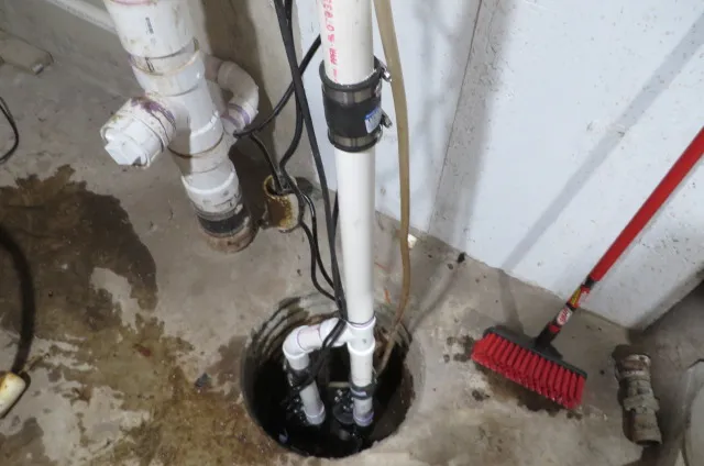 After: a new sump pump and white PVC discharge in the same pit